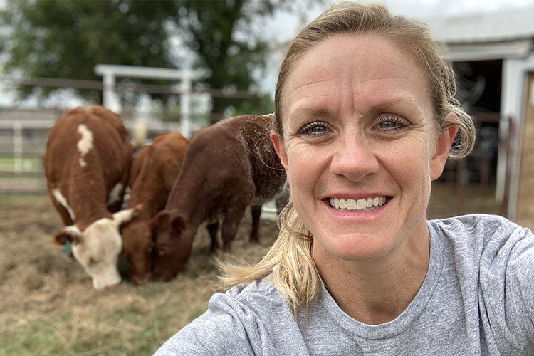 Julia poses with cattle in the background.