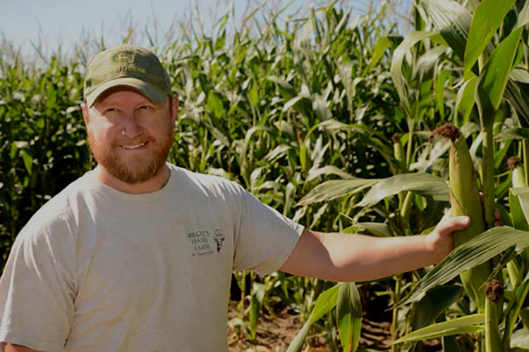 Clayton, standing in his corn field, is a fourth-generation dairy farmer.