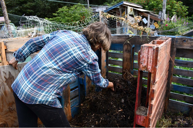 Woman handling compost in a compost bin.