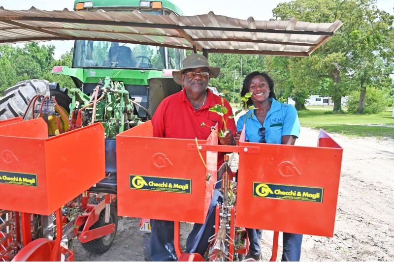 Customer and FSA employee sit in planting machine hooked to tractor.