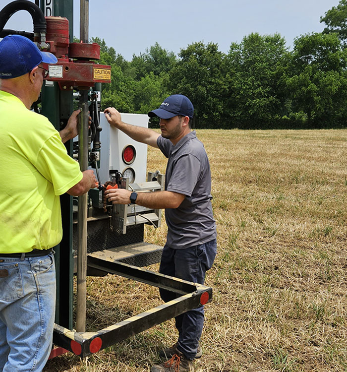 Two people operating a soil sample machine