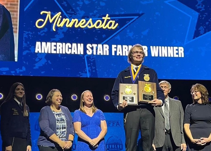 Person posing on a stage with plaques