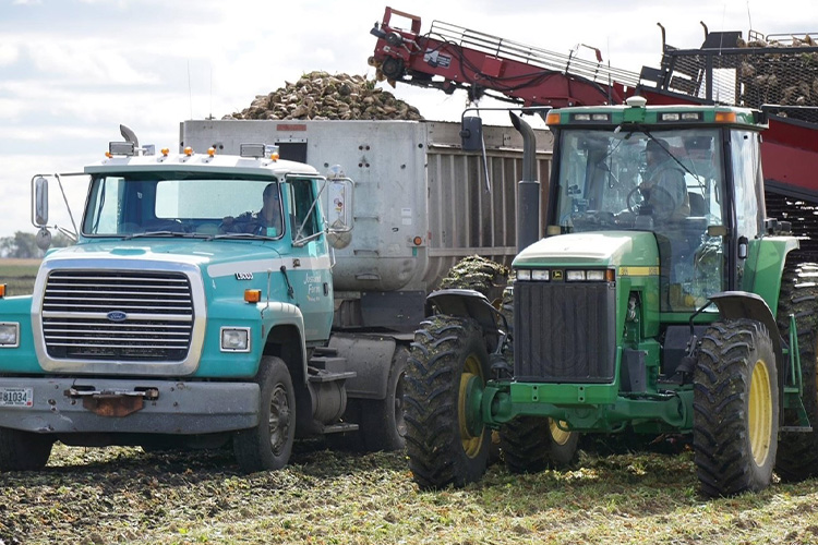 Tractor filling a truck with cut crops