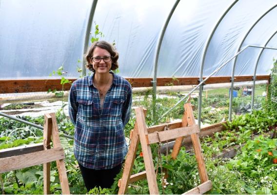 Person standing in a high tunnel green house.
