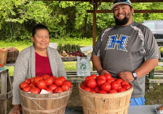 Two people standing in front of baskets of persimmons