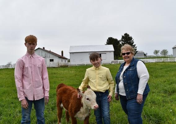 Three people standing with a calf