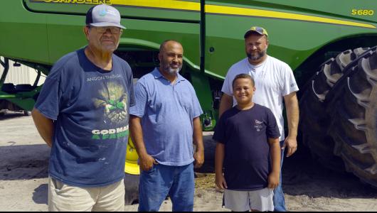 Four people standing in front of a tractor